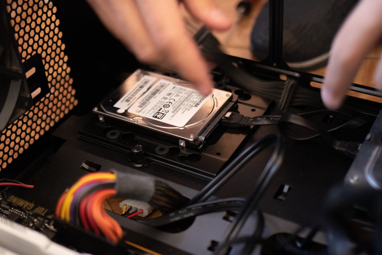 gallery-06 Hands installing a hard drive in a computer case, emphasizing technology and connectivity.