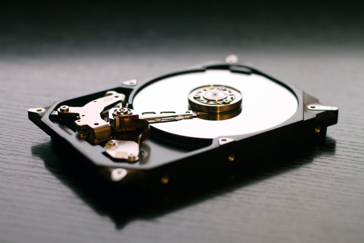services-01 An open hard drive is displayed on a wooden surface, showcasing its internal components and metallic details.