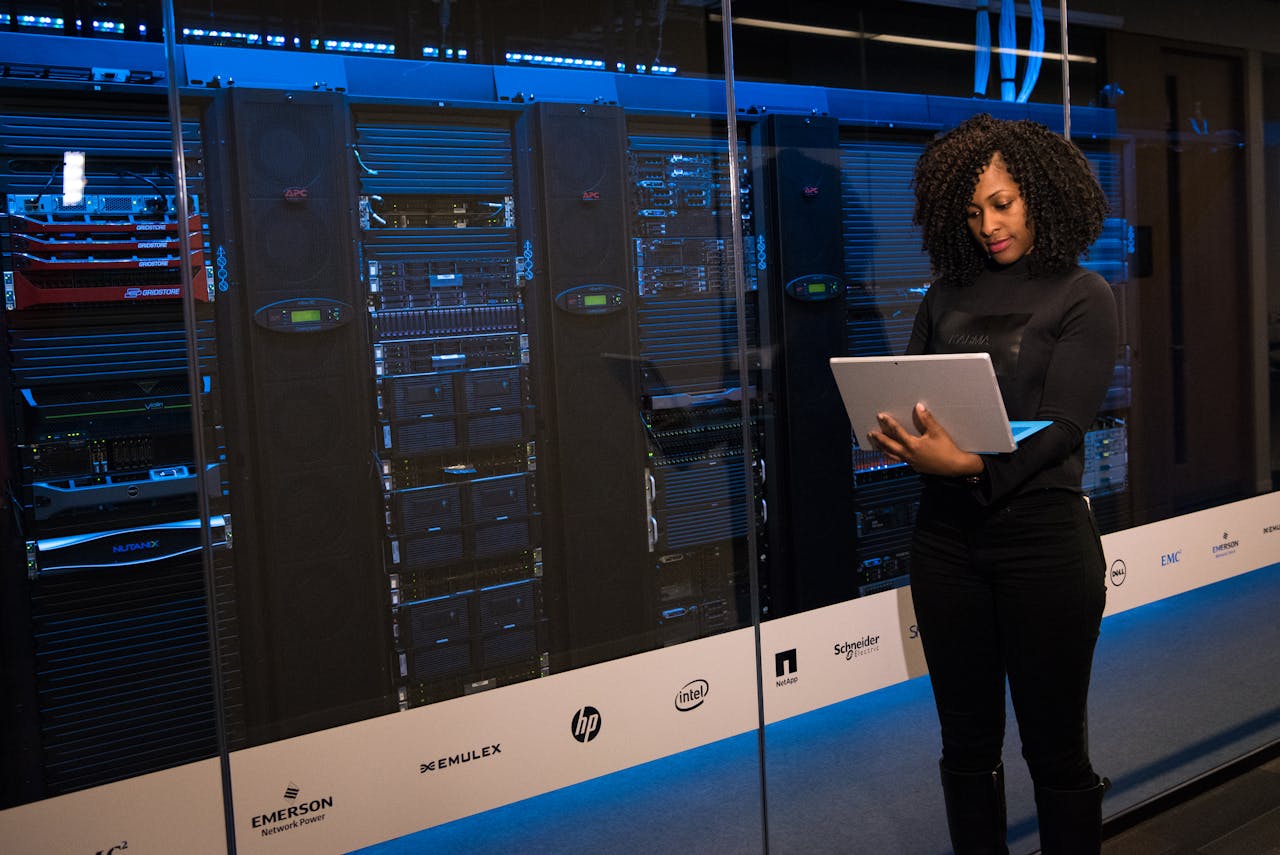 gallery-01 A female engineer using a laptop while monitoring data servers in a modern server room.